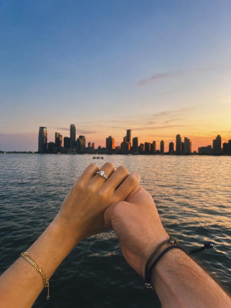 Nuestras manos y el anillo con el skyline al atardecer